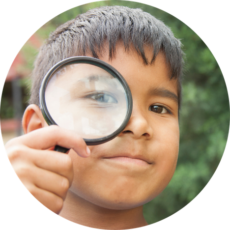 young boy looking through magnifying glass